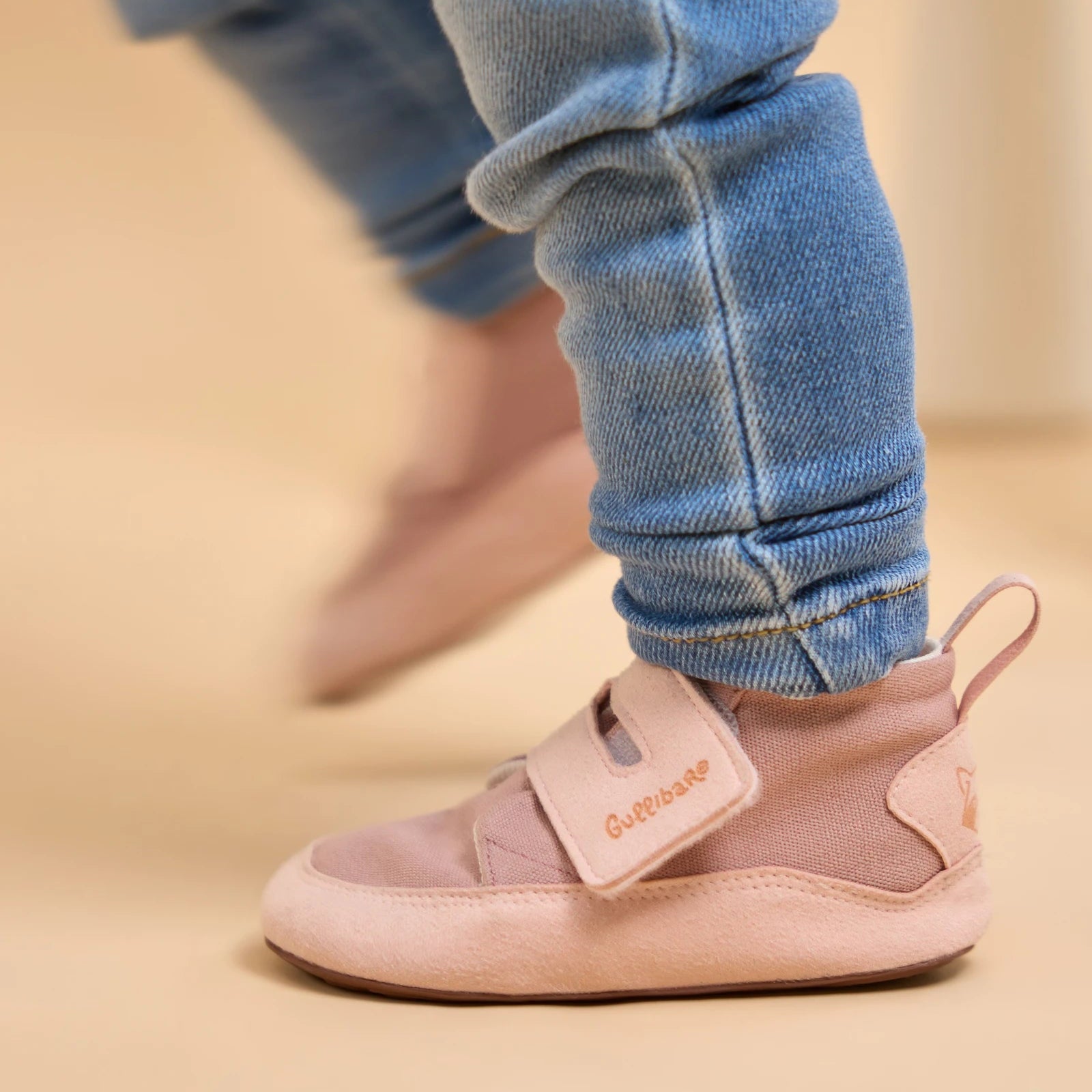 Niño con boticas rosadas Gullibare y pantalón de mezclilla, calzado respetuoso que acompaña sus primeros pasos.