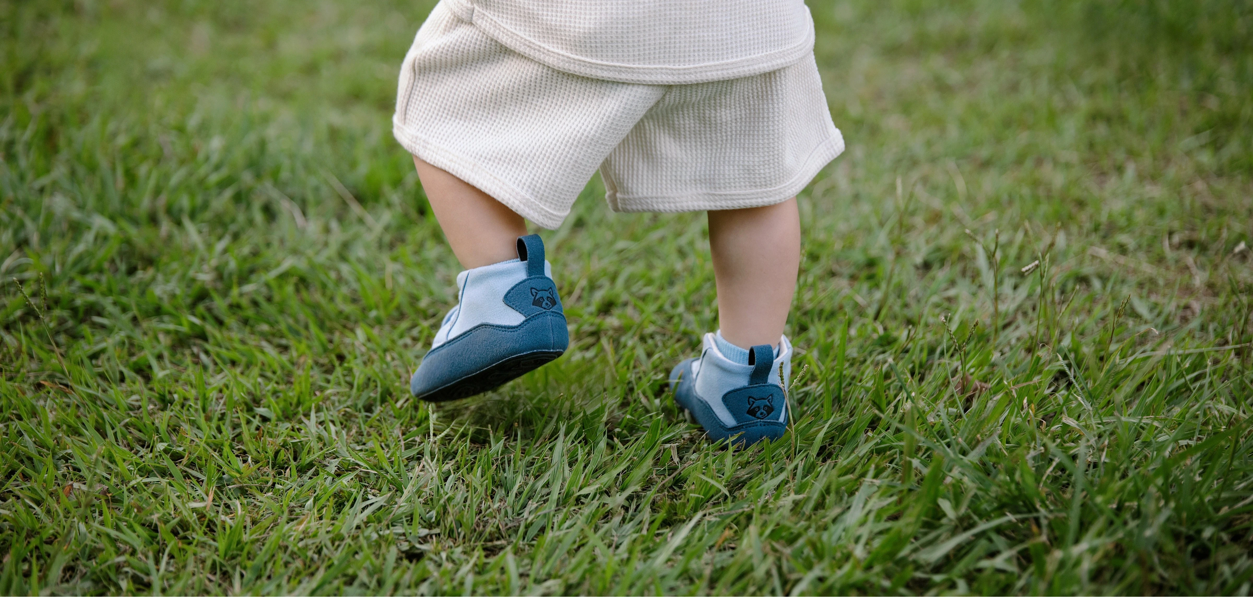 Niño caminando sobre césped con calzado respetuoso Gullibare en color azul, promoviendo movimiento natural y pasos libres.