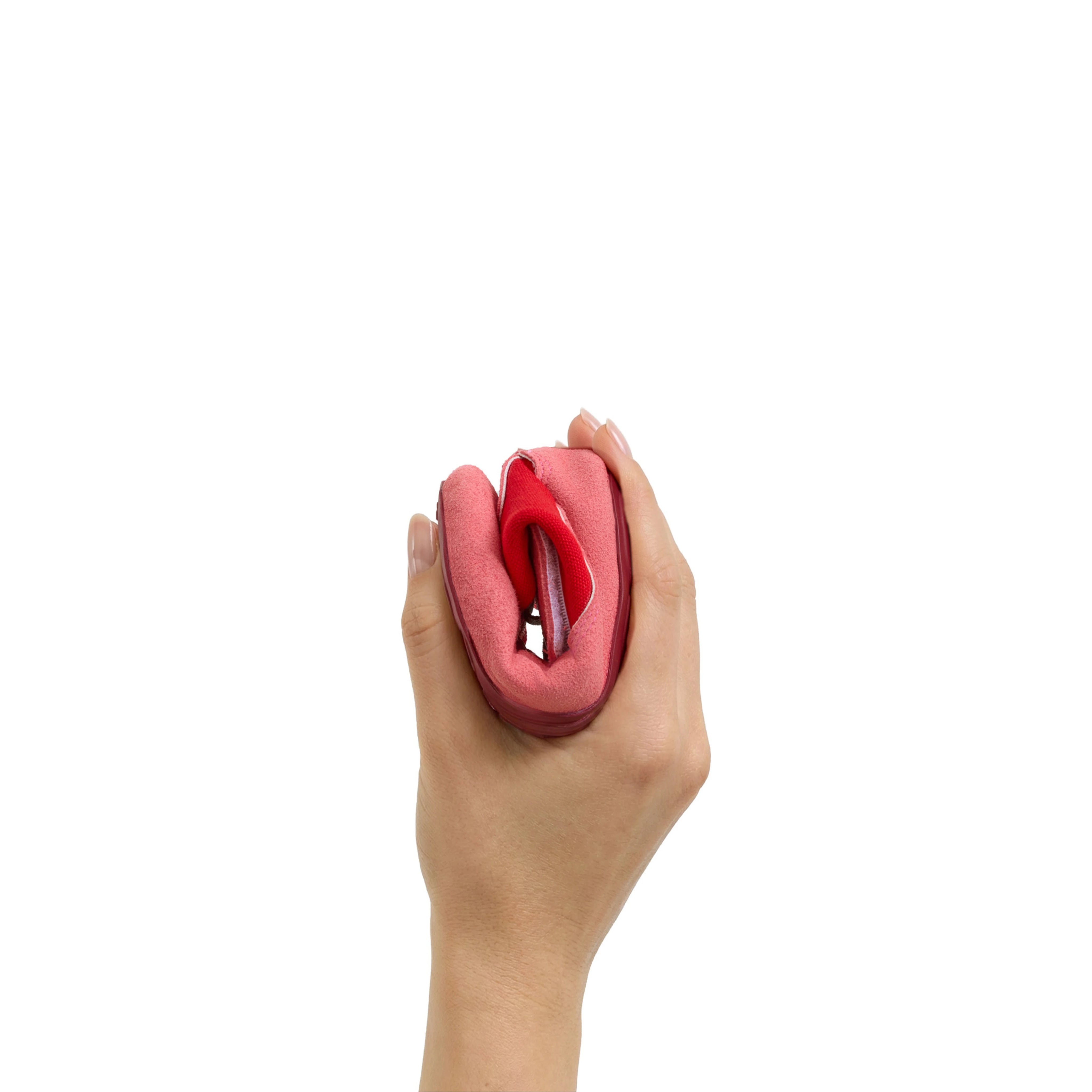 Calzado respetuoso Gullibare en color rojo para bebé, doblado con una mano para mostrar su flexibilidad sobre fondo blanco.