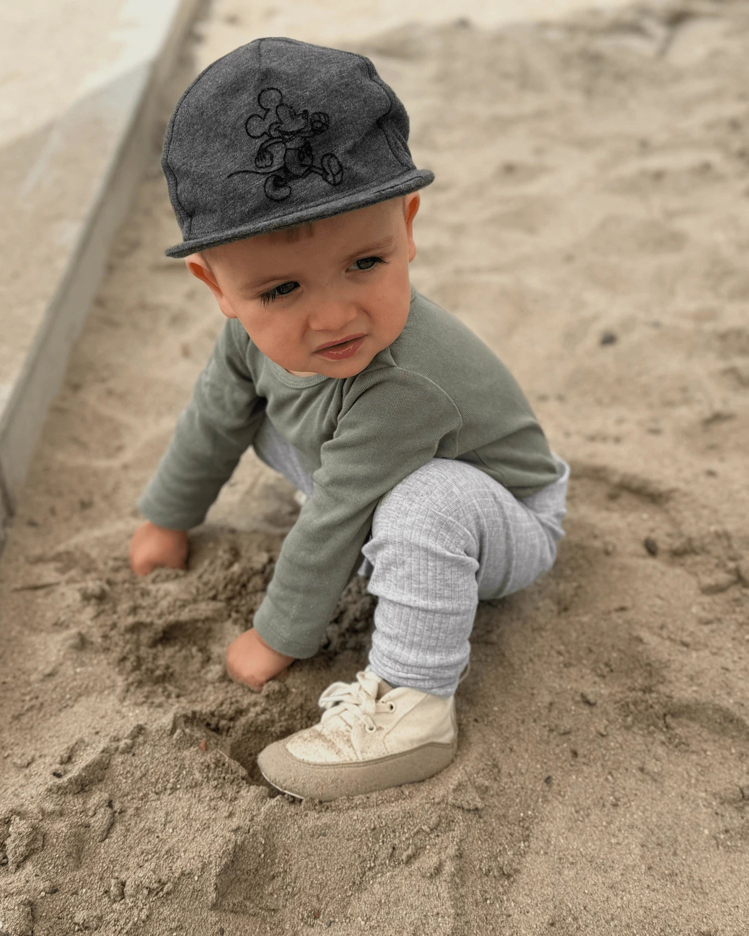Niño pequeño explorando la arena y el entorno natural mientras se mueve libremente.