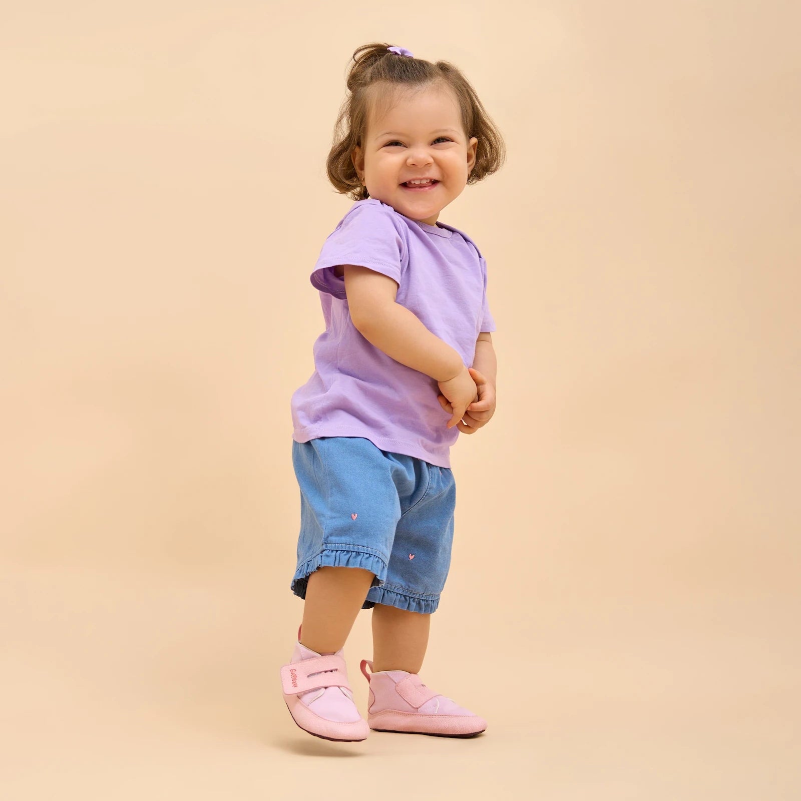 Niña feliz con boticas rosas Gullibare, calzado respetuoso que acompaña sus primeros pasos con libertad y ternura.