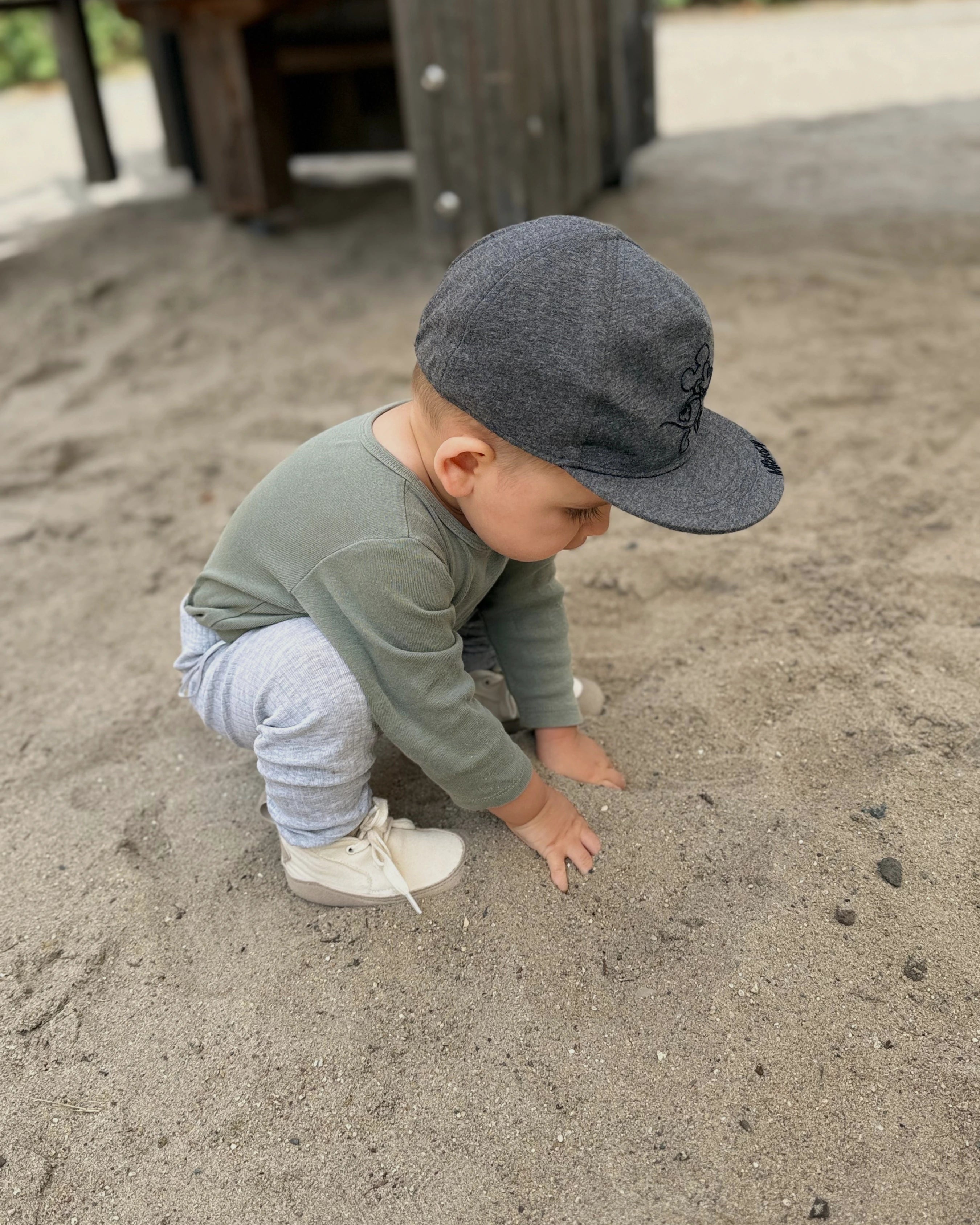 Bebé explorando la arena durante sus primeros pasos con calzado respetuoso Gullibare.