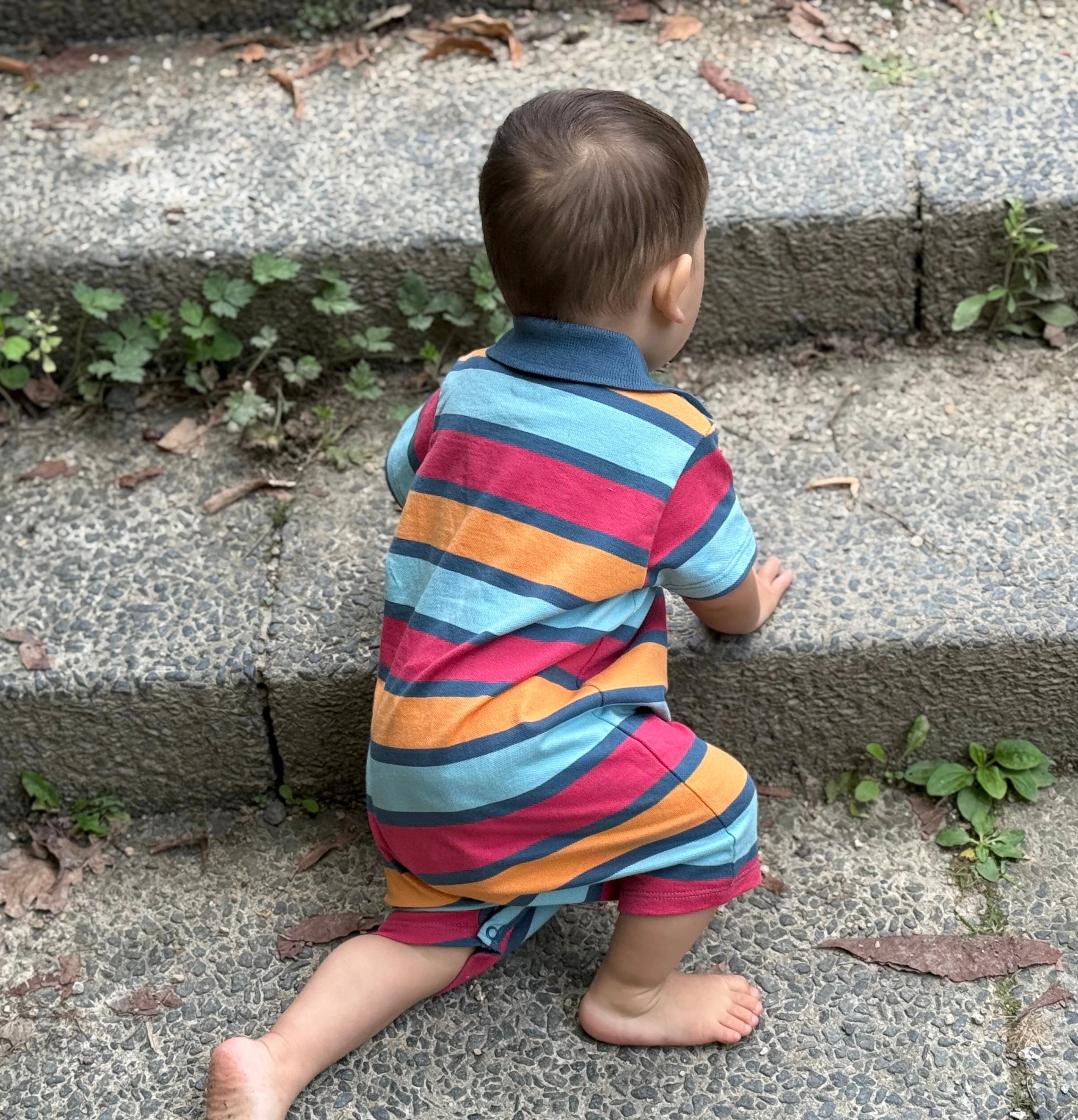 Bebé descalzo subiendo un escalón de piedra, explorando el entorno con libertad y desarrollando equilibrio y fuerza de forma natural.