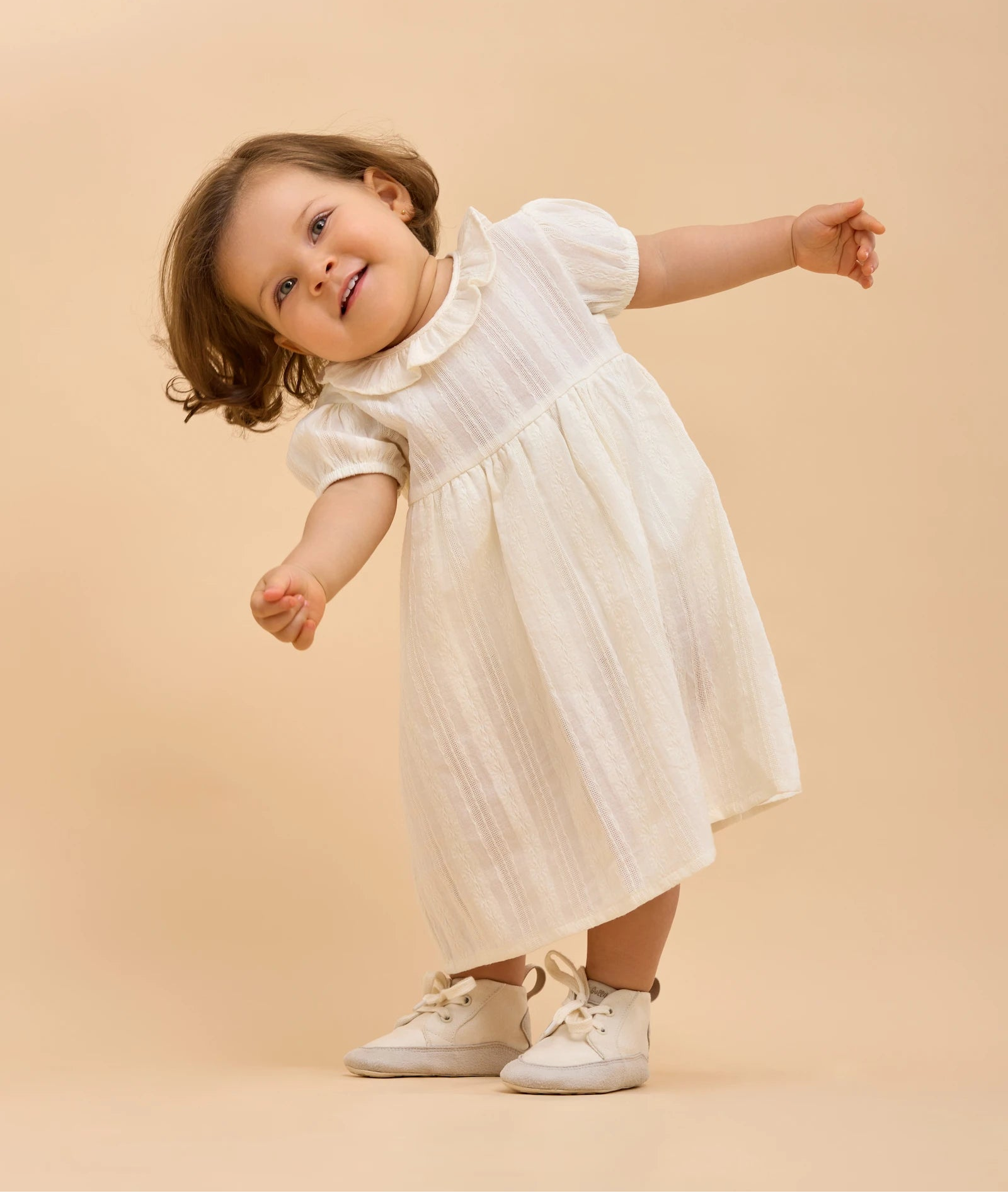 Niña sonriente jugando con boticas Gullibare beige, calzado barefoot hecho a mano que acompaña cada paso con suavidad y libertad.