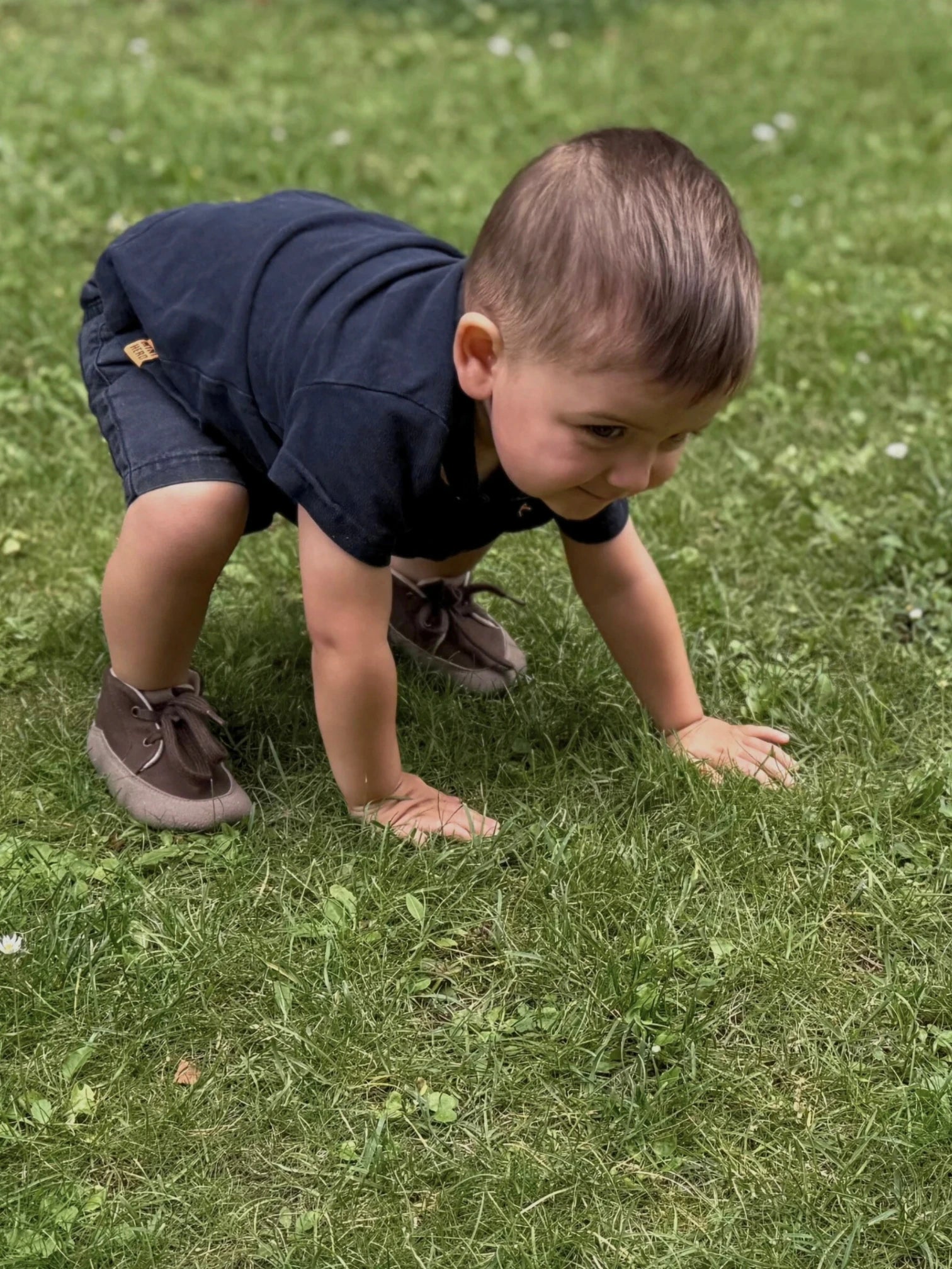 Niño jugando sobre el césped con zapatos de calzado respetuoso infantil Gullibare de color marrón.