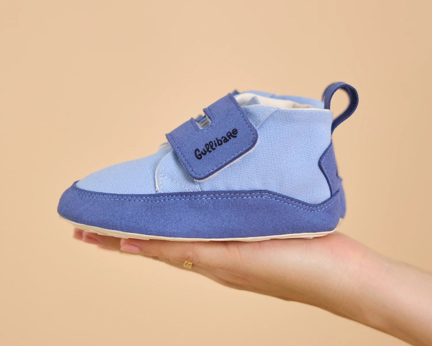 Botica Cielo Gullibare en tono azul pastel, sostenida en una mano, mostrando su diseño respetuoso, suave y flexible para los primeros pasos.
