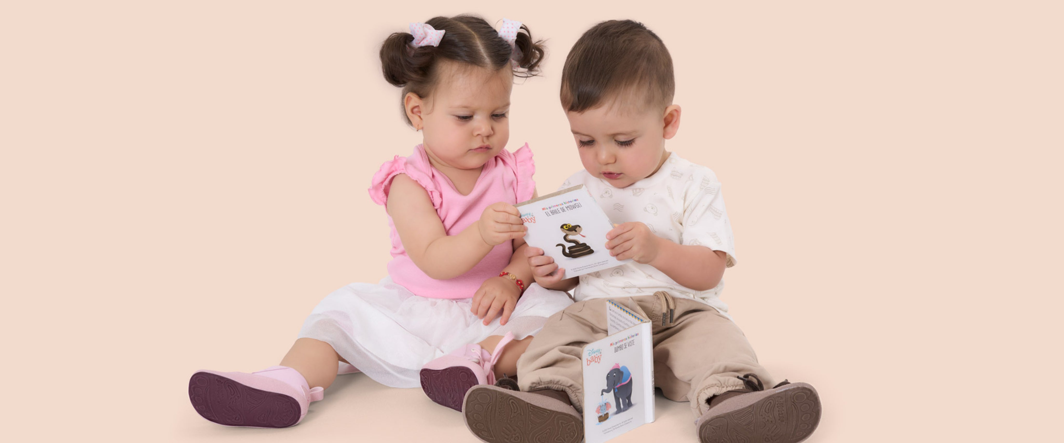 Dos niños pequeños sentados en el suelo descubren con curiosidad unas boticas Gullibare®, símbolo de los primeros pasos con libertad y cuidado natural.